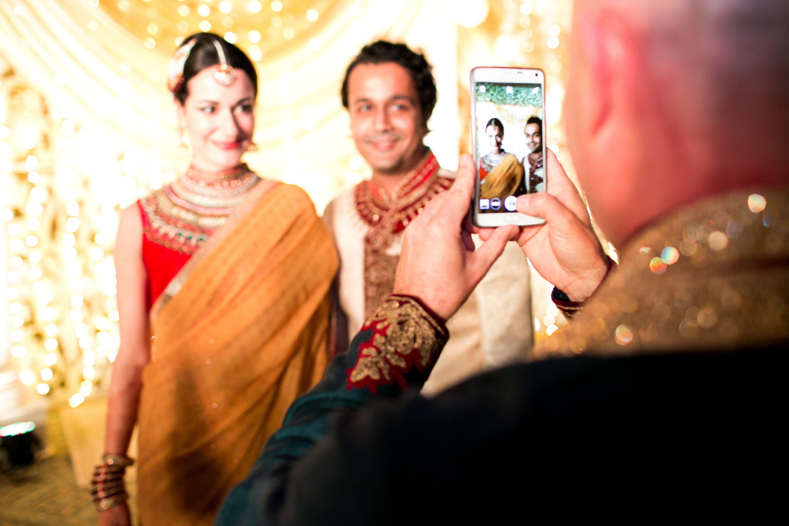 man takes picture of hindu wedding couple on his smartphone